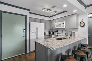 A modern kitchen with a central island, built-in appliances, and a clock on the wall. - Lakeview #9 - Paradise By The Gulf (Miramar Beach)
