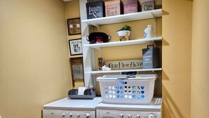 A laundry room with a washing machine, dryer, and shelves above containing laundry supplies.