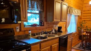 A wooden cabin kitchen with a stove, sink, and cabinets.
