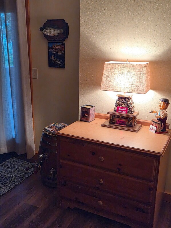 A wooden dresser with a lamp and a small statue on top.