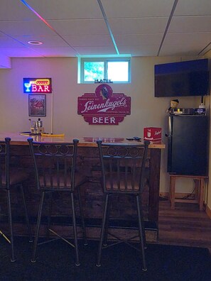 Eine Bar mit einer Neonreklame, einem alten Bierwerbeschild und einem an der Wand befestigten Fernseher.