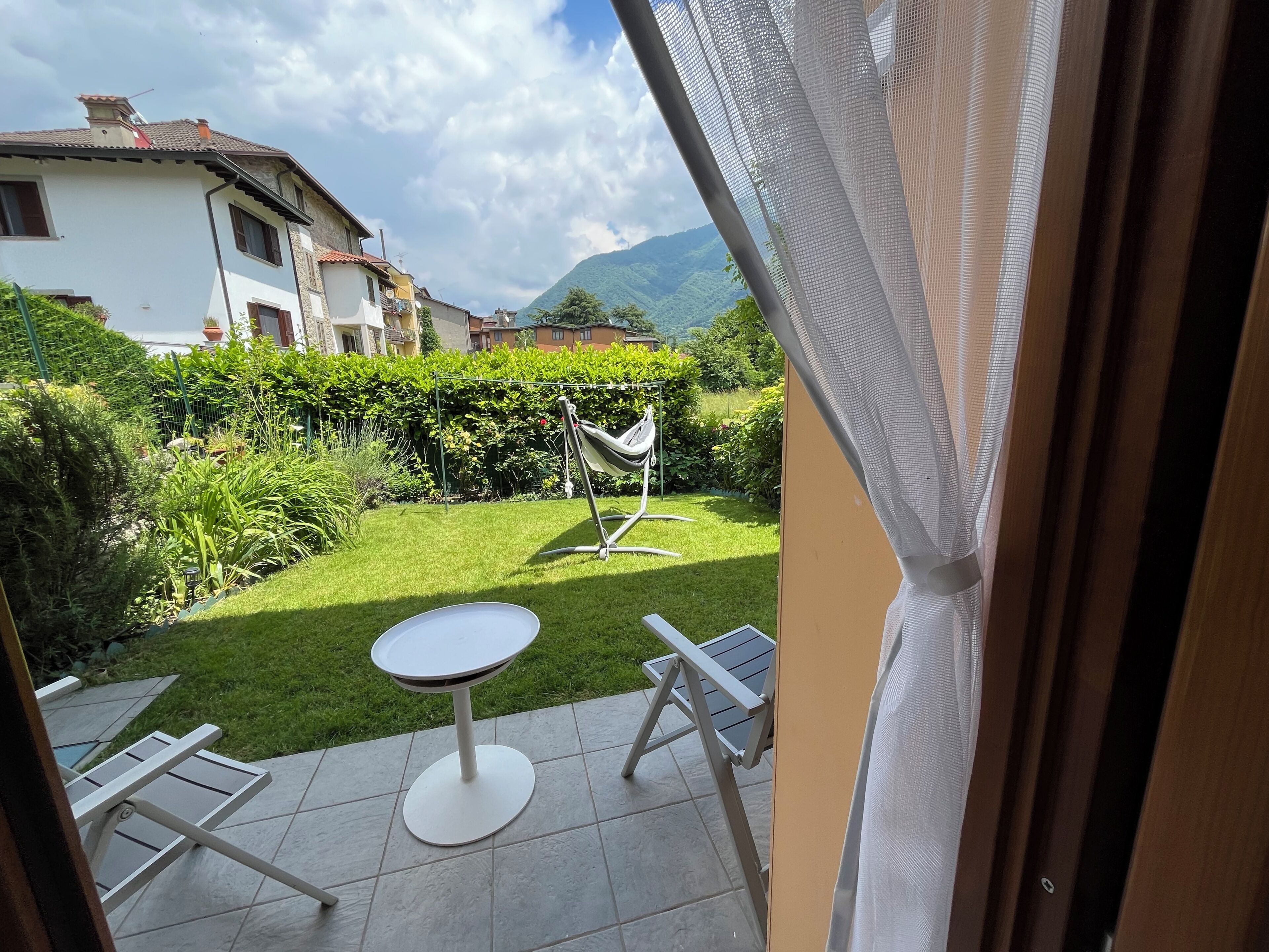 A patio with a table and chairs, a hammock, and a view of a mountain and houses.
