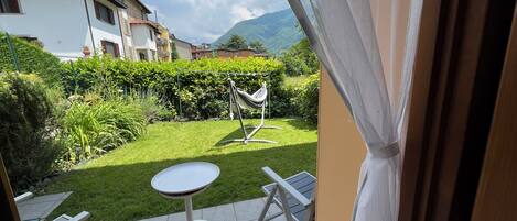 A patio with a table and chairs, a hammock, and a view of a mountain and houses.