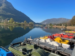 A calm lake with boats docked, surrounded by mountains and trees. - Charming apartment with a pool and breathtaking views. (Spinone Al Lago)