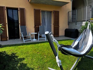 Eine Terrasse mit Gartenmöbeln, darunter eine Hängematte, Stühle und ein Tisch.