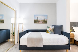 Ein Schlafzimmer mit einem Bett, Nachttischen, einem Spiegel und einem Bild an der Wand.
