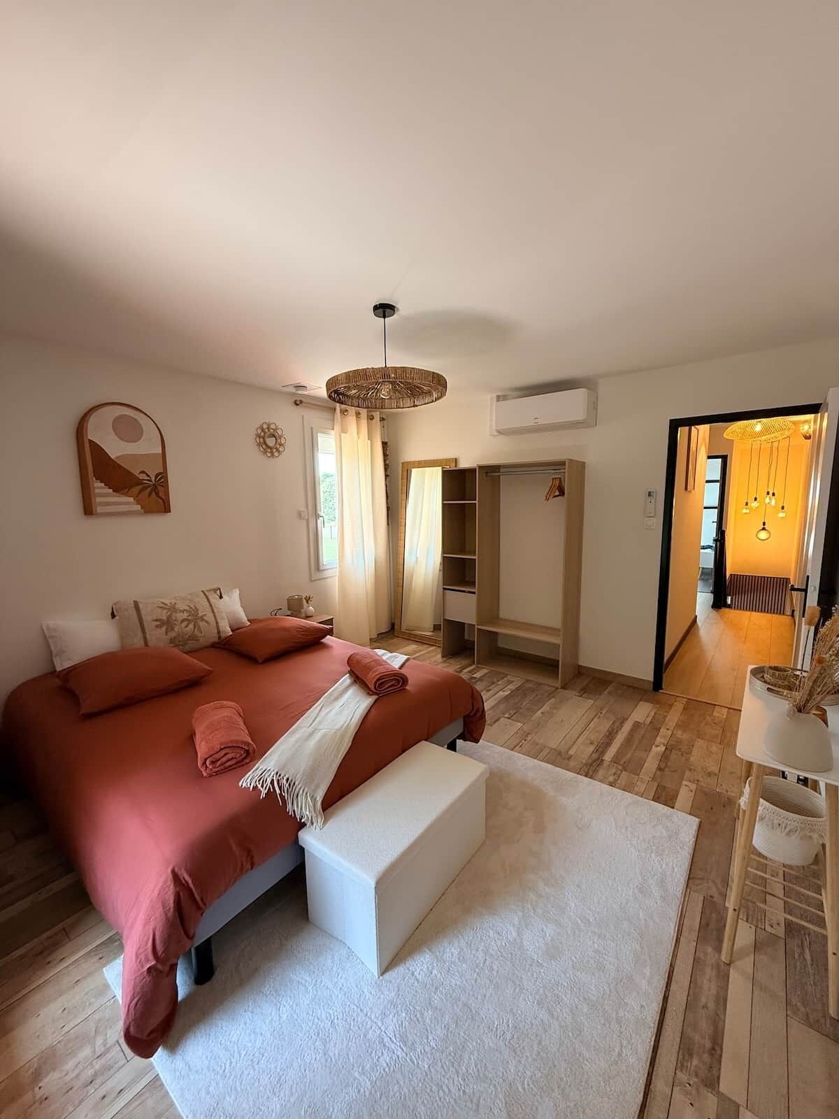 A bedroom with a large bed, bedside tables, a wardrobe, and a view into another room.