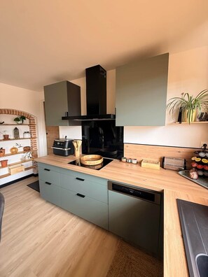 A modern kitchen with a central island, built-in appliances, and a brick accent wall.