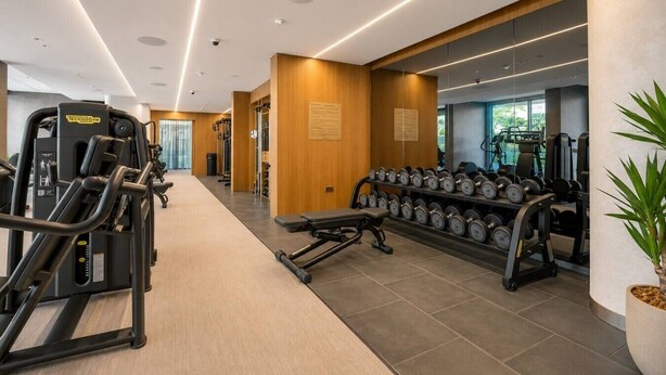 Une salle de sport moderne équipée de matériel d’exercice, de supports pour les poids et dotée d’un intérieur propre et bien éclairé.