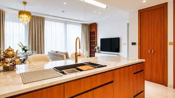 A modern kitchen with a large island, wooden cabinets, and a built-in TV.