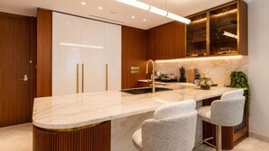 Une cuisine moderne dotée d’un plan de travail en marbre, de tabourets de bar et d’un meuble à vin intégré.