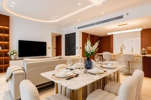 A modern dining area with a marble table, comfortable seating, and a television in the background. - Ellington Beach House (Dubai)