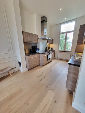 A modern kitchen with wooden cabinets, a built-in oven, and a window providing natural light.