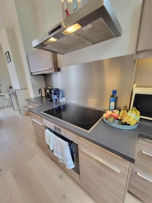 A modern kitchen with a black induction cooktop, stainless steel cabinets, and a built-in oven.