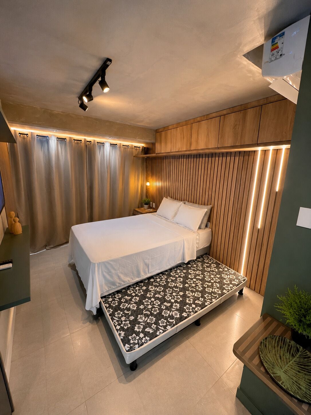 Ein modernes Schlafzimmer mit Bett, Nachttisch und einer Sitzbank mit Blumenmuster.