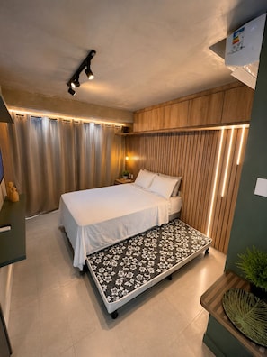A modern bedroom with a bed, bedside table, and a bench with a floral pattern.