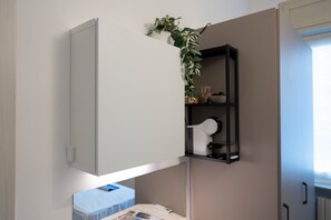 Ein gemütlicher Raum mit integriertem Schrank, einer kleinen Ablage mit Dekoration und einem Nachttisch mit einem Buch.