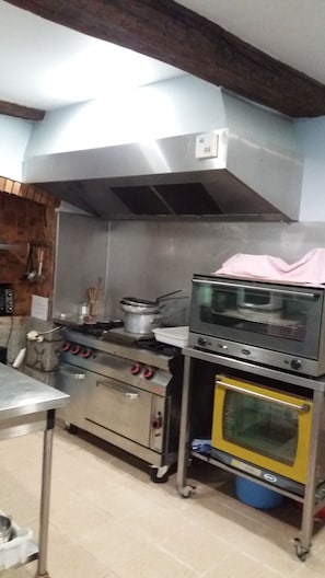 Cocina con electrodomésticos de acero inoxidable, extractor de humos y piso de baldosas.