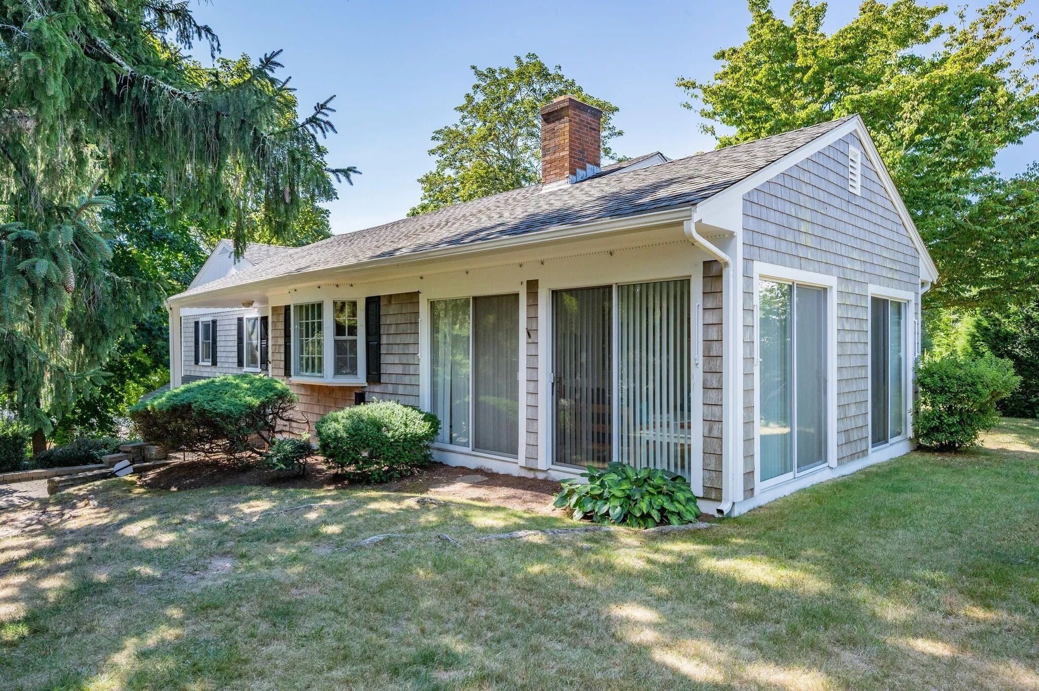 A single-story house with a covered porch, a chimney, and a well-maintained lawn.