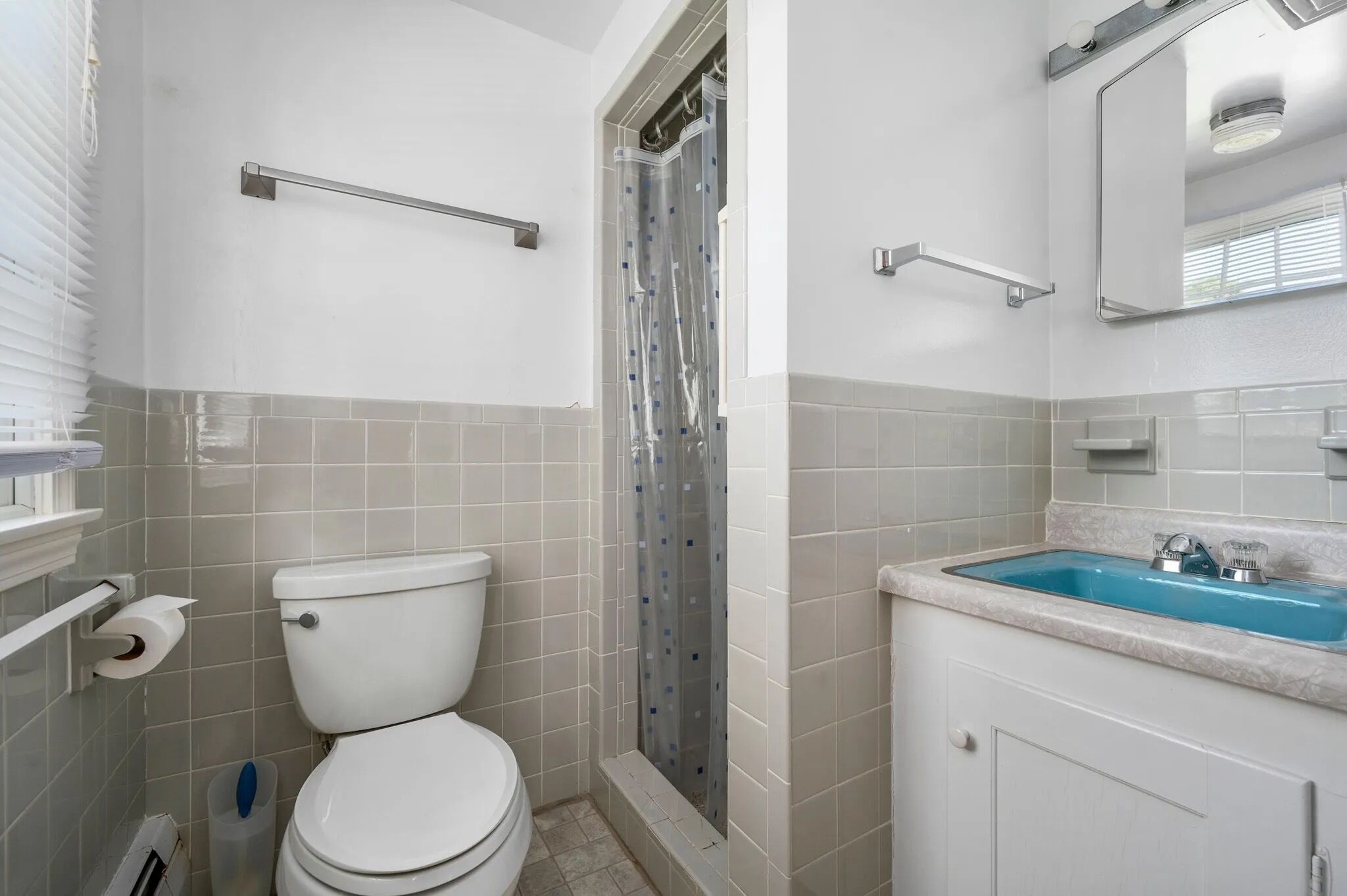 A bathroom with a toilet, shower, and sink.