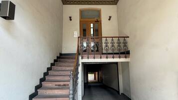A staircase leading to a landing with a decorative ceiling and a wooden door.
