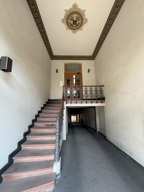A staircase leading to a landing with a decorative ceiling and a wooden door. - StayPrime Wiesbaden Premium Design Apartment 65-inch Smart TV Streaming (Wiesbaden)