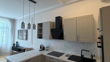 A modern kitchen with marble countertops, a built-in oven, and a stainless steel sink.