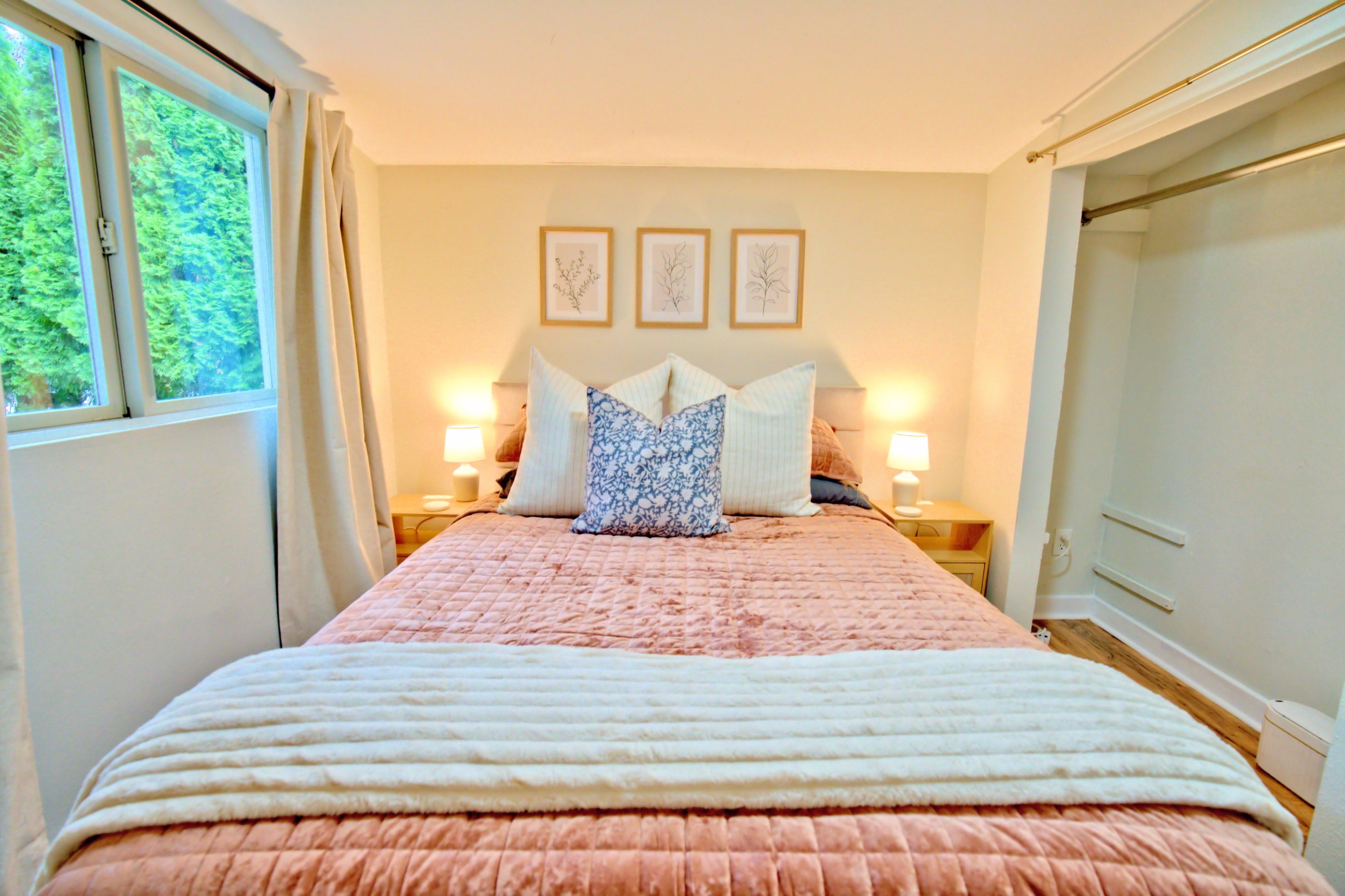 A bedroom with a bed, bedside lamps, a window, and a door.