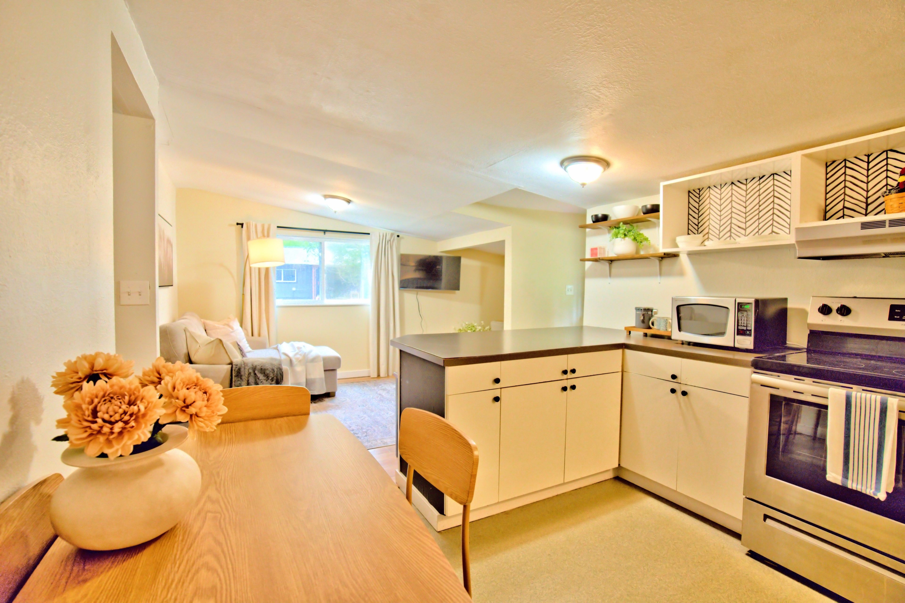 A compact kitchen with a dining table, chairs, a microwave, and an oven.