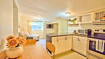 A compact kitchen with a dining table, chairs, a microwave, and an oven.