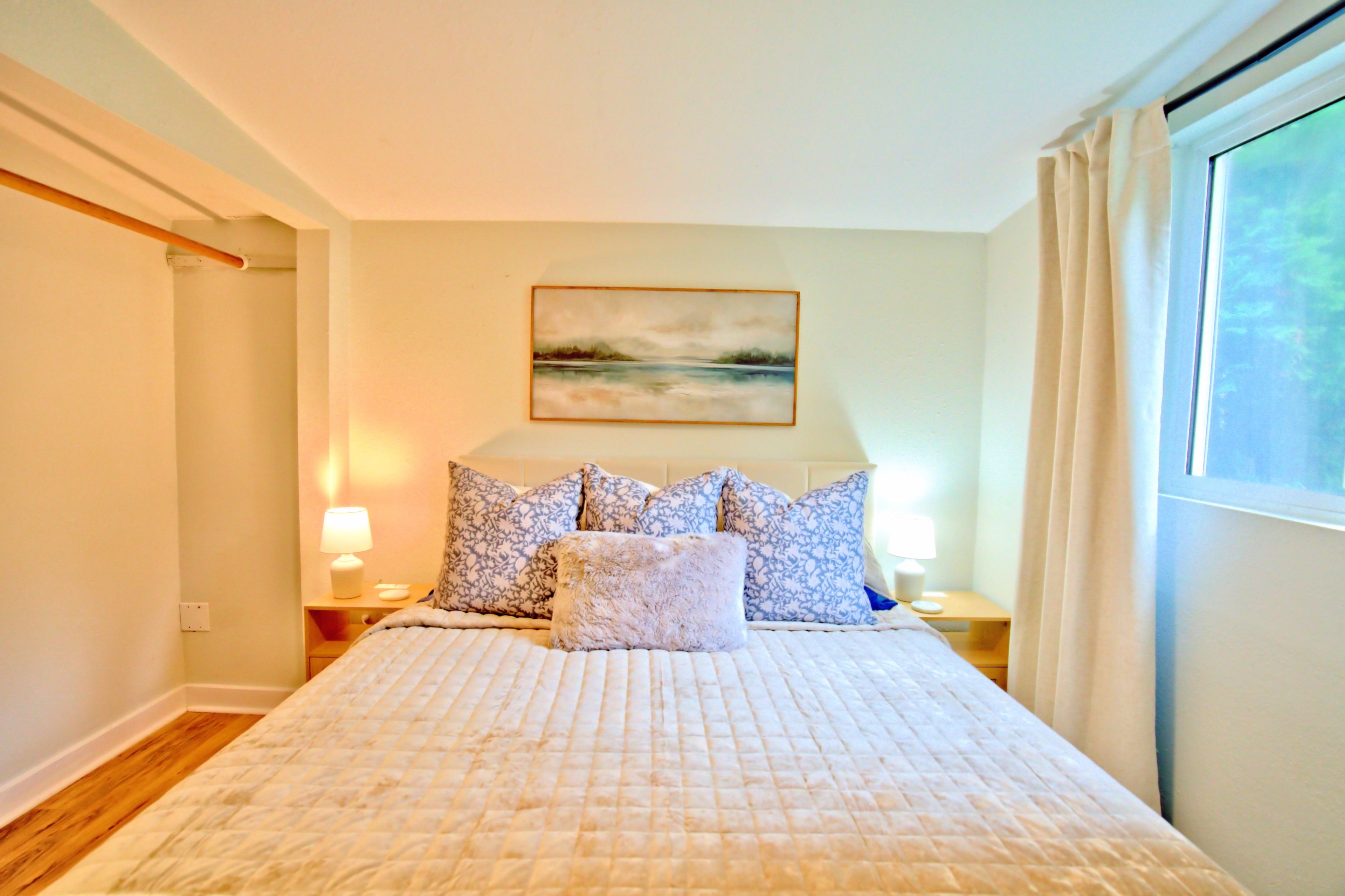 Una camera da letto con un letto grande, un quadro appeso al muro e una finestra con tende.