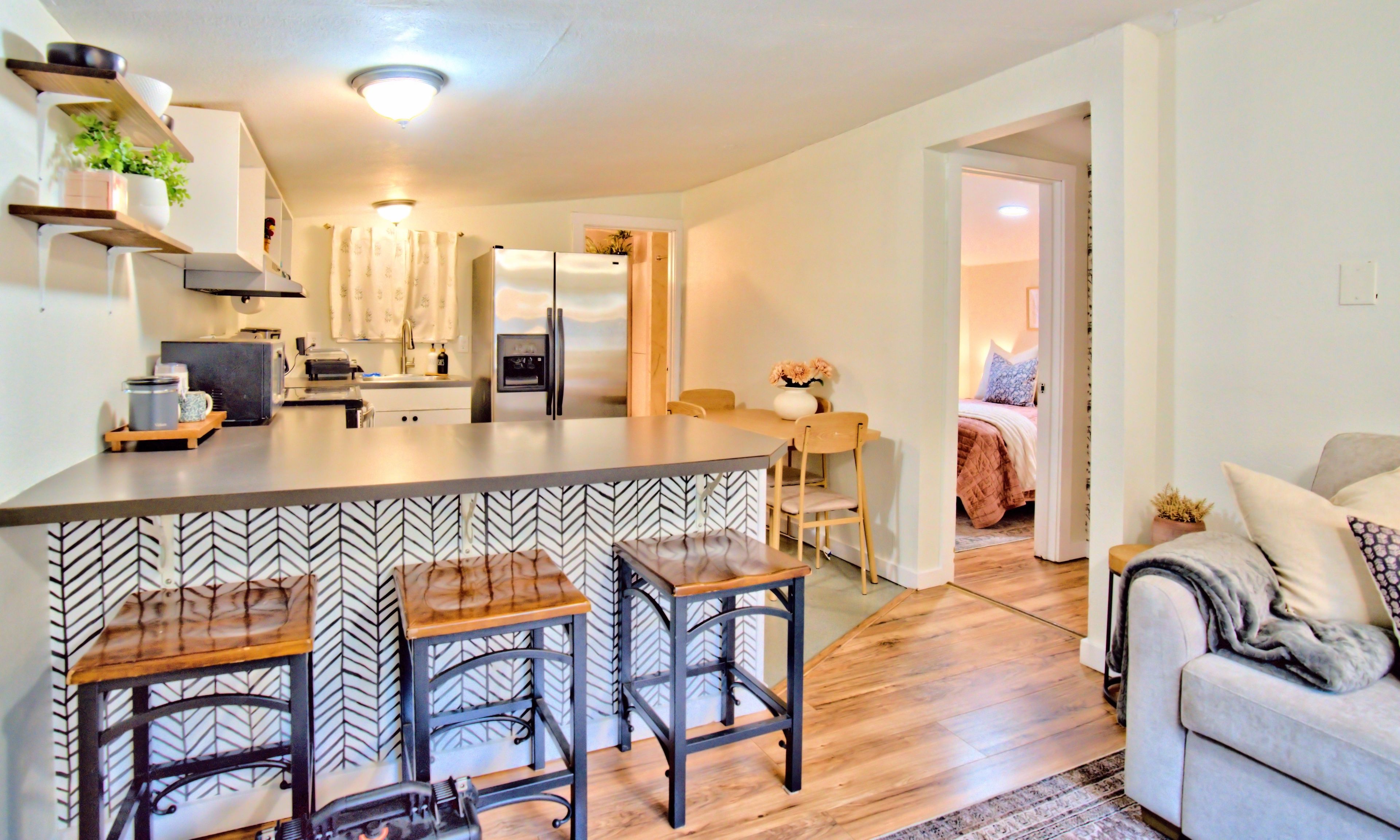 A modern kitchen with a central island, bar stools, and a dining area with a table and chairs.