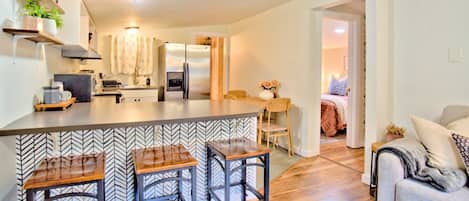Cocina moderna con una isla central, taburetes de bar y un comedor con mesa y sillas.