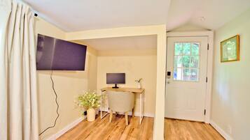 A room with a desk, chair, television, and a door with a window.