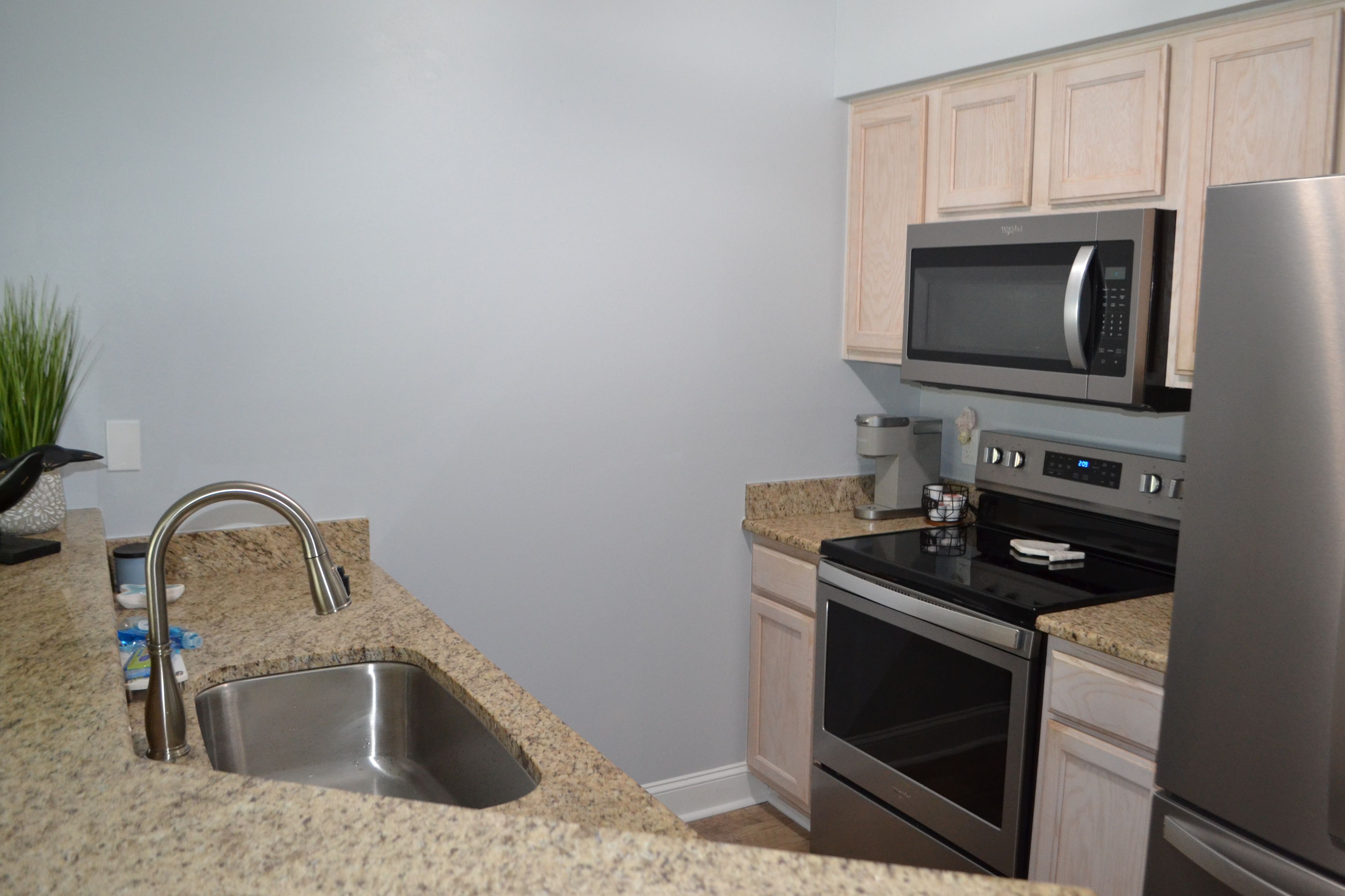 A kitchen with granite countertops, stainless steel appliances, and light wood cabinetry.