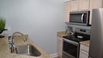 A kitchen with granite countertops, stainless steel appliances, and light wood cabinetry.