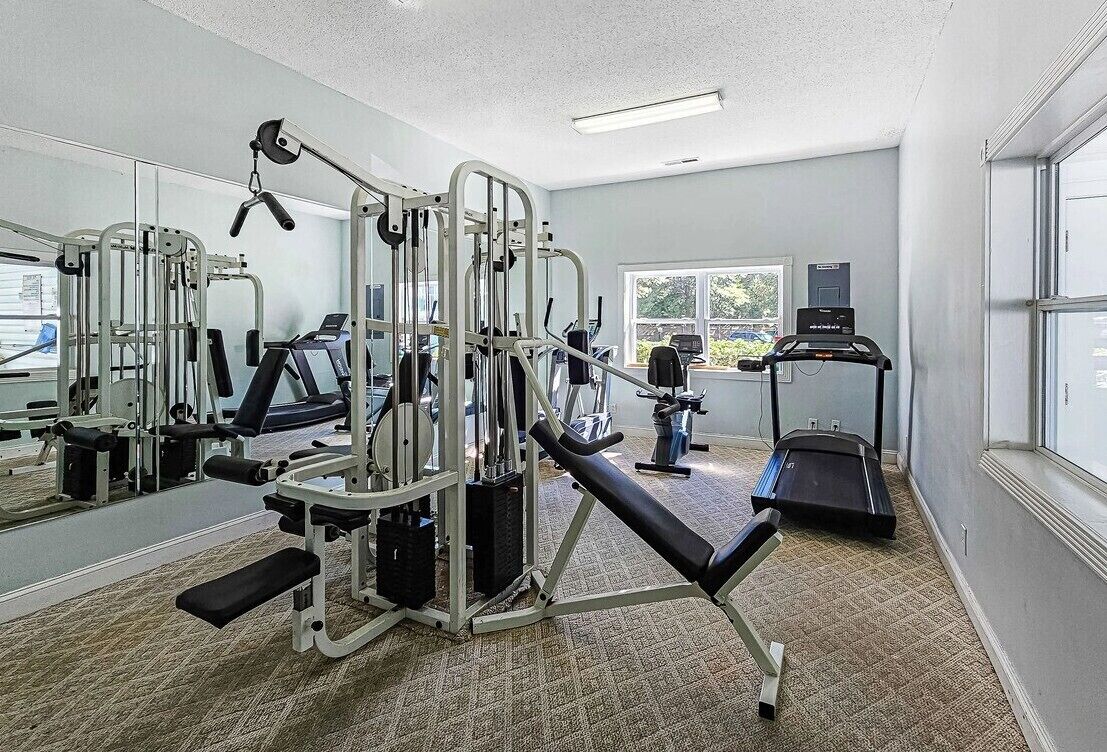 A gym with various exercise equipment, a treadmill, and a large mirror.