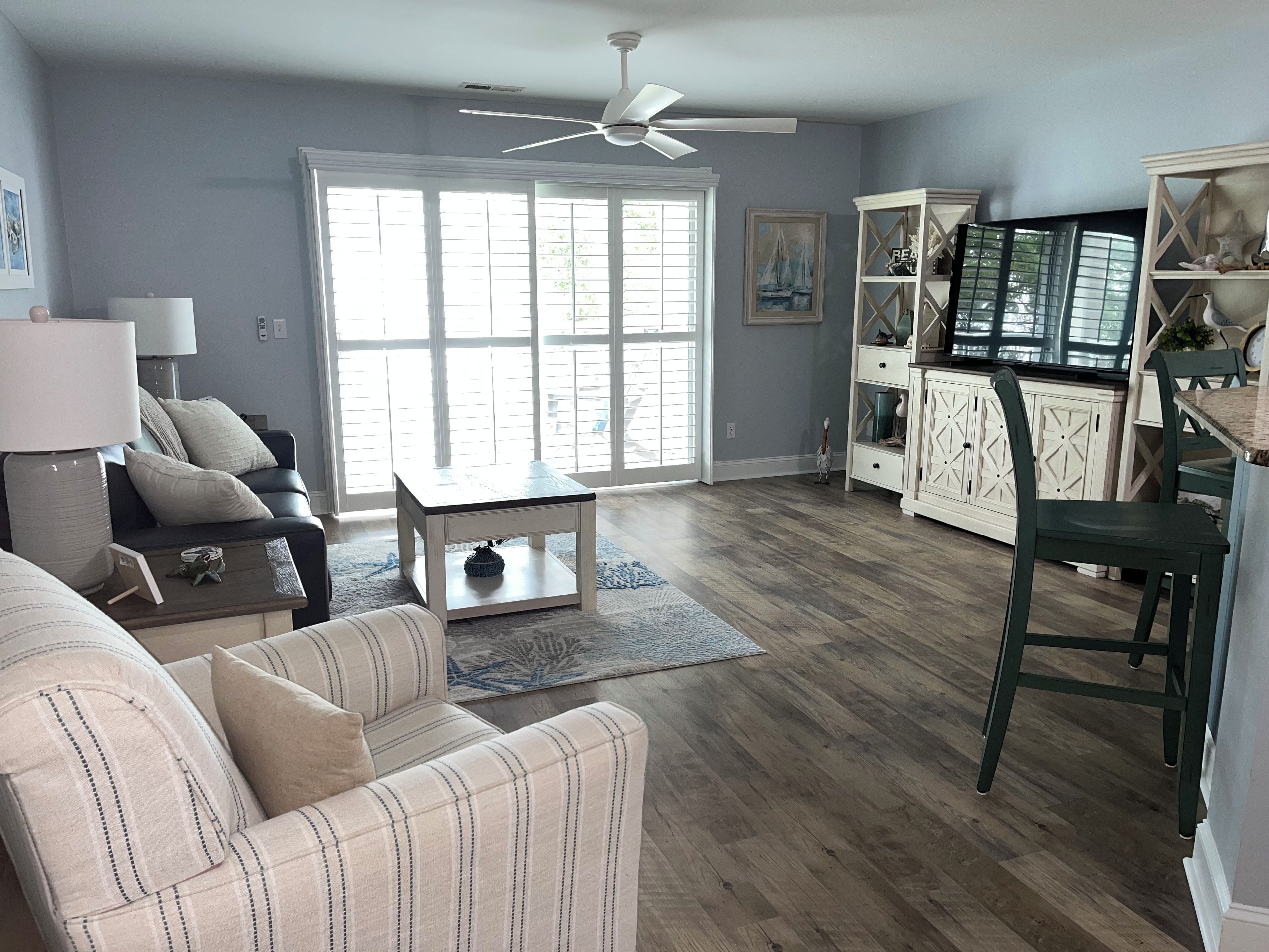 A living room with a sofa, coffee table, and a dining area with chairs and a cabinet.