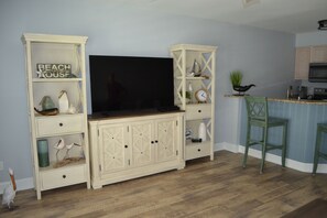 A kitchen with a wooden countertop, a built-in TV, and a bar area with a green chair.