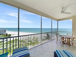 Ein Balkon mit Blick auf Strand und Meer, inklusive Tisch und Stühlen sowie Deckenventilator.