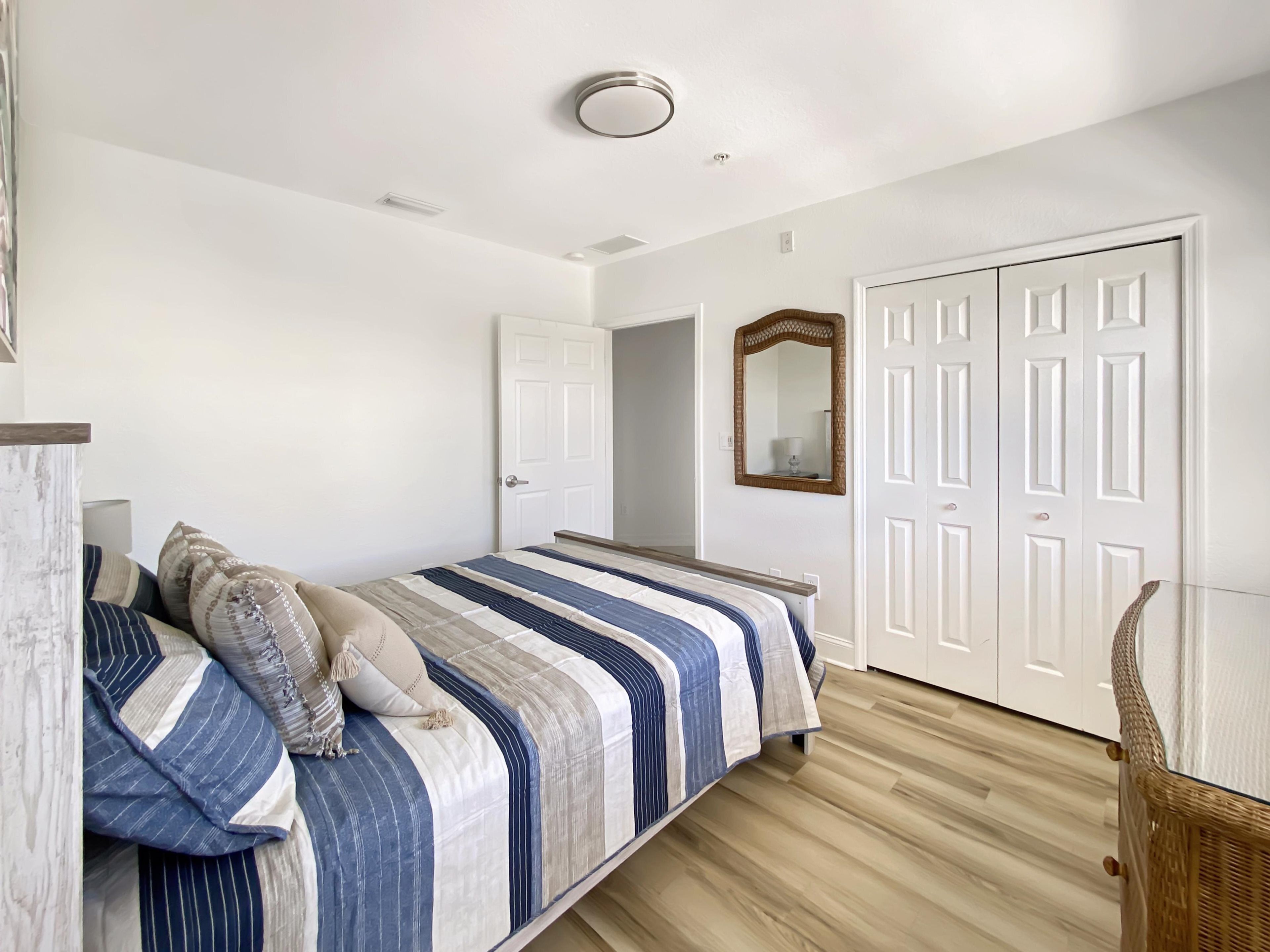 Een slaapkamer met een bed, een deur en een spiegel.