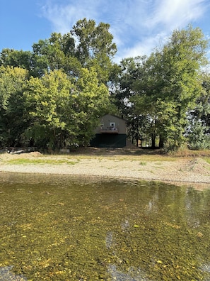 Una casa con un balcone, circondata da alberi e da uno specchio d'acqua.