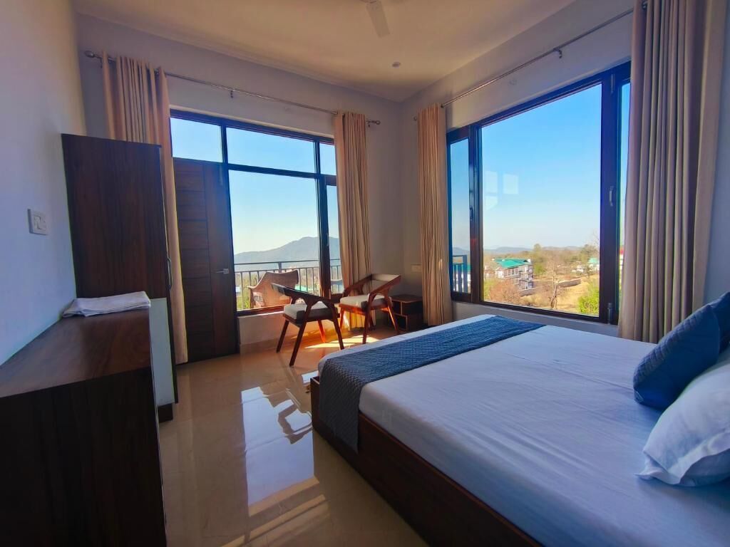A hotel room with a large bed, a desk, and a view of the outdoors.