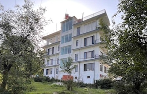 A multi-story residential building with balconies, surrounded by trees and greenery. - AeroVale Lodge (Bir)