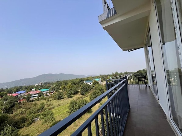 A balcony with a view of a green landscape and distant buildings. - AeroVale Lodge (Bir)