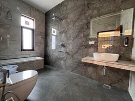 Un baño moderno con una bañera independiente, un espejo grande y un revestimiento de mármol.
