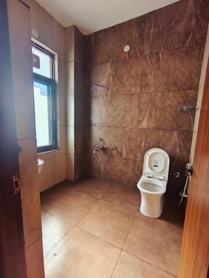 A bathroom with a toilet, shower, and a window. - AeroVale Lodge (Bir)