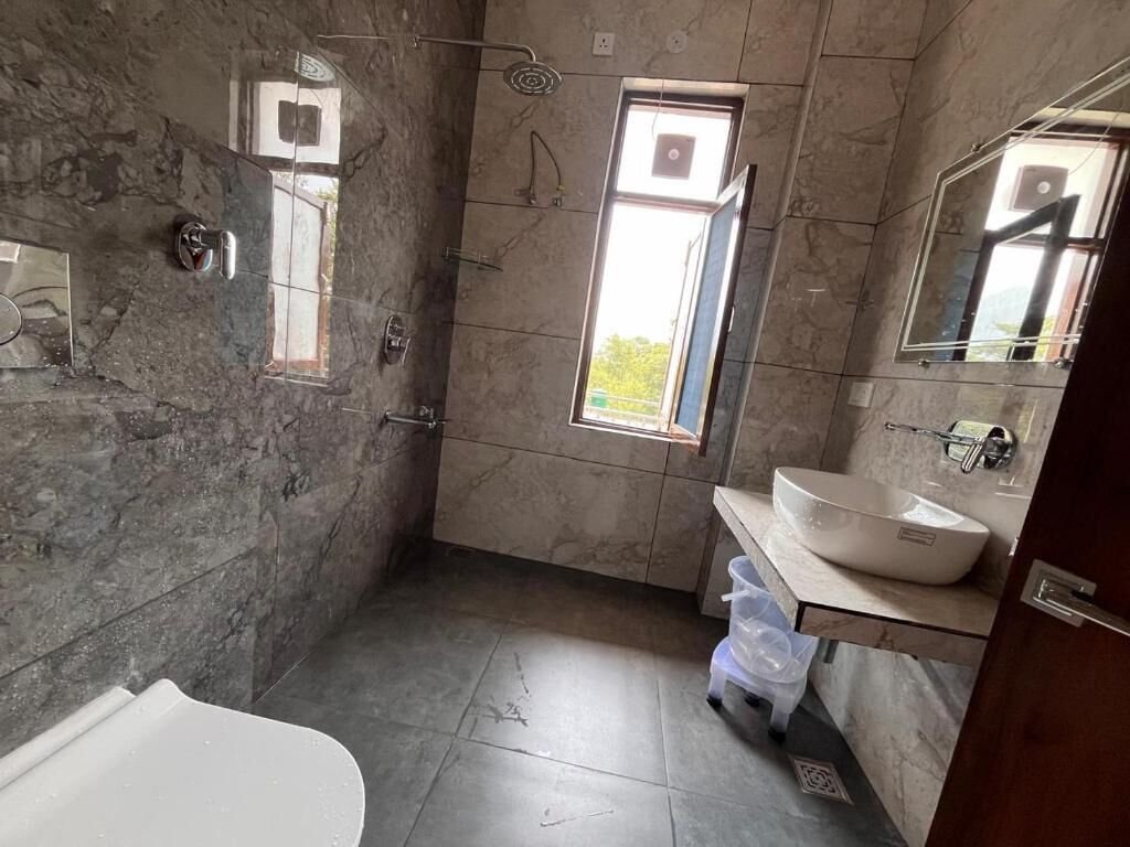 Een badkamer met een bad, wastafel, raam en douche.