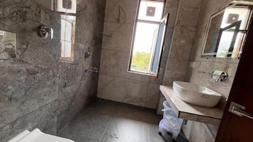 Een badkamer met een bad, wastafel, raam en douche.