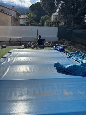 A rooftop with a blue tarp, a statue, and a white wall. - Charming family home with a private pool (Laroque-des-Albères)